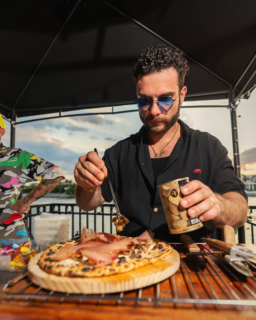 Chef finishing a pizza at a live event