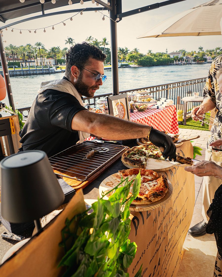 Chef Mike Bancale serving pizza at a live station by the water